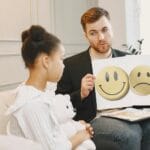 Logopeda z dzieckiem używają kart emocji podczas zajęć