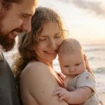 Rodzice trzymają niemowlę na sopockiej plaży o zachodzie słońca