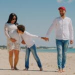 Uśmiechnięta ciężarna kobieta spaceruje z partnerem po sopockiej plaży
