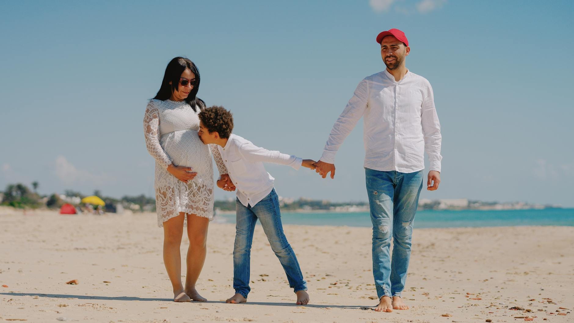 Uśmiechnięta ciężarna kobieta spaceruje z partnerem po sopockiej plaży