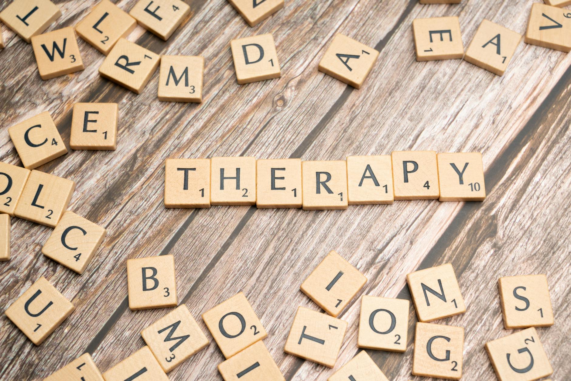 Drewniane kostki z literami tworzące słowo therapy na drewnianym tle