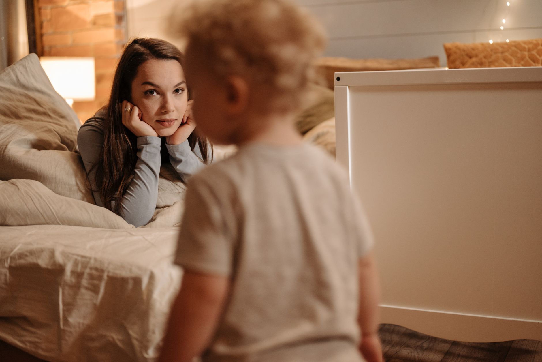 Mama delikatnie przytula małe dziecko w ciepło oświetlonej sypialni