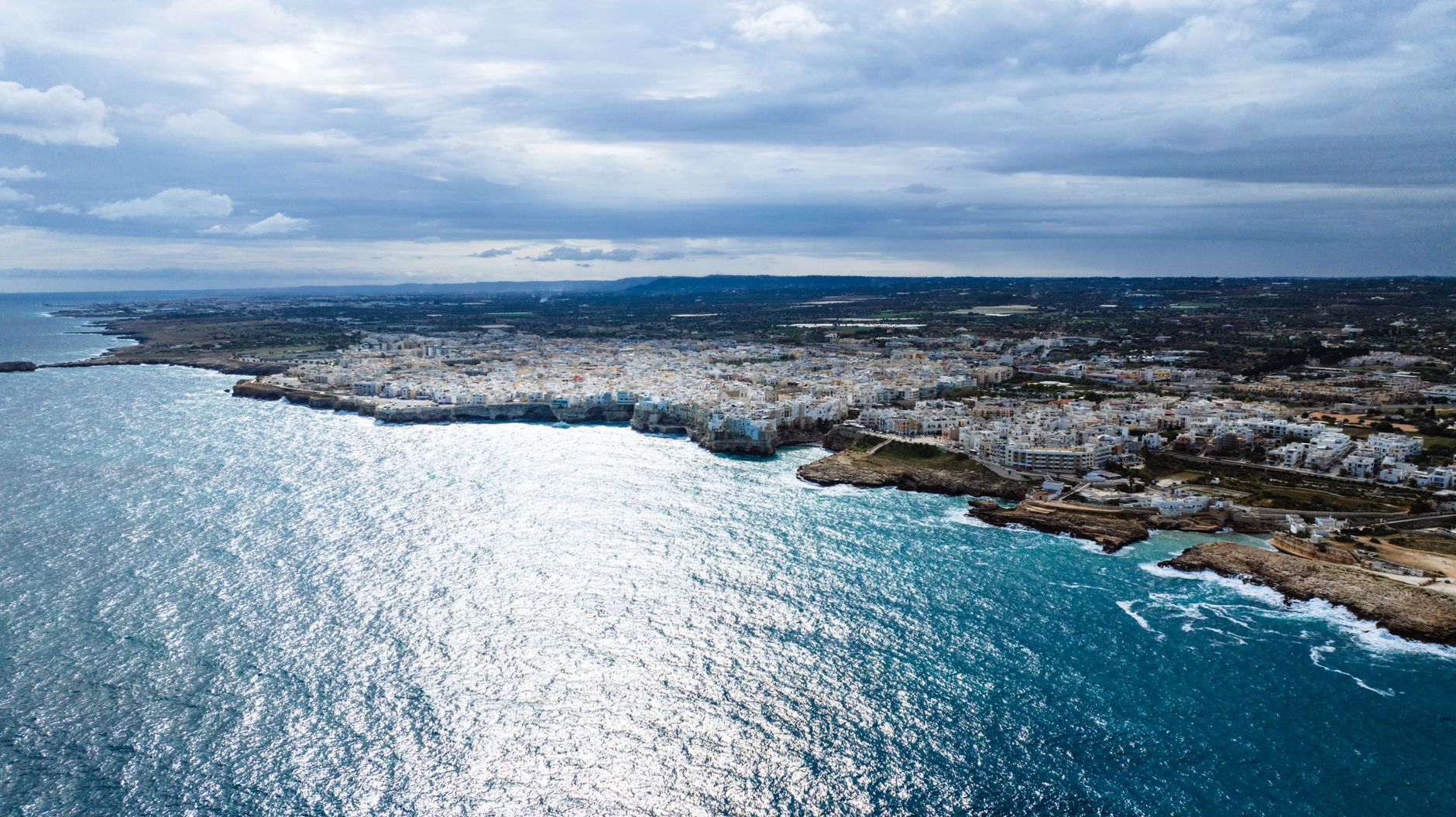Polignano a Mare z lotu ptaka, białe zabudowania nad turkusowym morzem